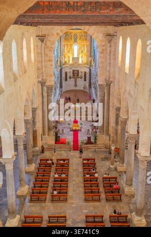 Großer Blick auf das Innere der Kathedrale von Cefalu mit Reihen von Bänken und Touristen in Cefalu, Sizilien, Italien Stockfoto