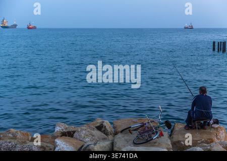 Ein Fischer am Limassol-Wellenbrecher bleibt bis zum Einbruch der Dunkelheit. Stockfoto