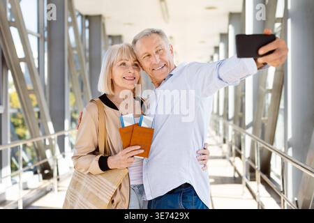 Glückliches reifes Paar, das am Flughafen ein Selfie mit Smartphone macht Stockfoto
