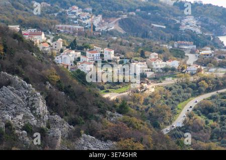 Ein malerisches Dorf am Hügel mit weißen Häusern, gewundenen Straßen und üppigem Grün in einer mediterranen Landschaft. Stockfoto