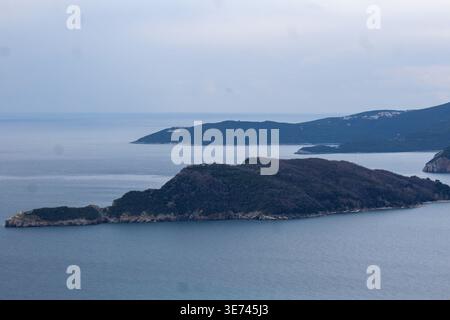 Luftaufnahme der Insel Sveti Nikola in der Nähe von Budva, Montenegro, ruhige Adria, bewölkter Himmel, natürliche Küstenlandschaft. Stockfoto
