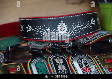 Villach, Österreich - 28. Juli 2025: Handgefertigter Ledergürtel mit detaillierter Stickerei auf Holzoberfläche, der traditionelle Handwerkskunst hervorhebt Stockfoto