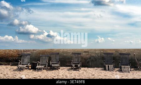 Svaneke, Dänemark 19-08-2017 Beschreibung: Leere Vintage-Liegestühle aus Holz an einem Sandstrand in Svaneke, Bornholm. Stockfoto