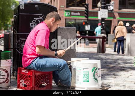 Ein Straßenkünstler in einem rosa Hemd spielt ein Schlagzeug auf einem Bürgersteig in Boston, Massachusetts, in der Nähe des TD Bank Gebäudes Stockfoto