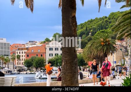 An einem sonnigen Herbsttag sitzen und spazieren Sie gemütlich entlang der Hafenpromenade in Split, Kroatien. Stockfoto
