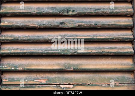 Extreme Nahaufnahme von verwitterter und abblätternder grüner Farbe auf Holzfenstern. Stockfoto