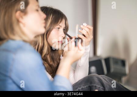 Junge Frau, die Make-up mit einem kompakten Spiegel aufträgt Stockfoto