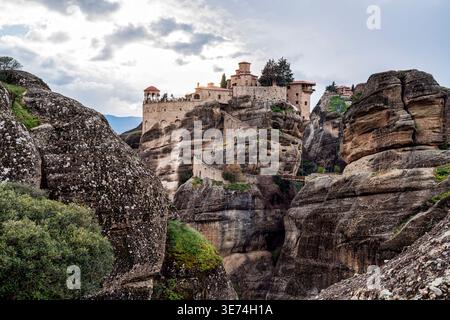 Großer Blick auf das Kloster Varlaam, das auf einer massiven Felssäule in Meteora, Griechenland, thront. Der historische orthodoxe Komplex erhebt sich über dramatischen Klippen unter einem Stockfoto