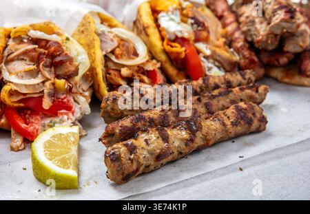Gegrillte Fleischspieße und mit Gyro gefüllte Pita-Brotwickel aus der Nähe Stockfoto