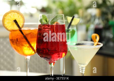 Verschiedene leckere erfrischende Cocktails in Gläsern drinnen, Nahaufnahme Stockfoto