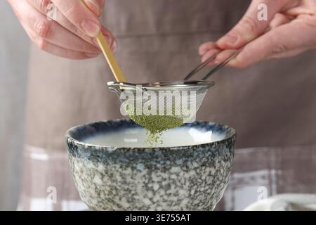 Frau, die Matcha-Pulver in eine Schüssel siebt, Nahaufnahme Stockfoto