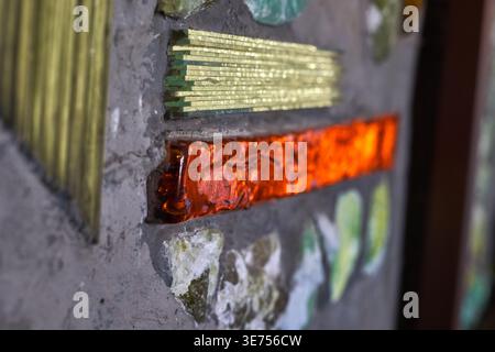 Nahaufnahme eines Mosaiks oder Glasgemäldes mit lebendigen Farbglasstücken, die in Beton oder Mörtel eingebettet sind. Das Bild zeigt Stockfoto