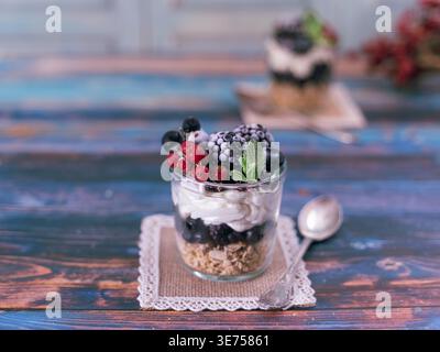 Aus nächster Nähe sehen Sie das mehrschichtige Beerendessert mit Creme auf farbenfrohem, strukturiertem Holzhintergrund Stockfoto