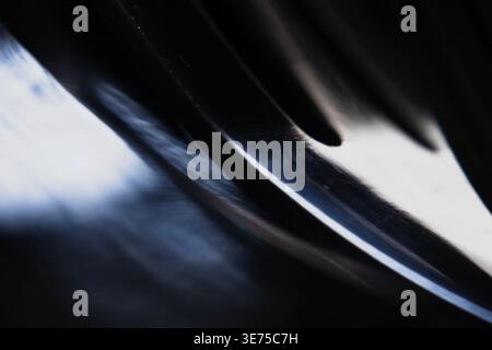 Abstrakte Nahaufnahme einer gekrümmten Chromfläche mit hellen Lichtreflexionen Stockfoto