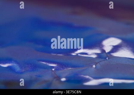 Blauer irisierender Hintergrund mit zerknitterter Folie und metallischen Reflexen Stockfoto