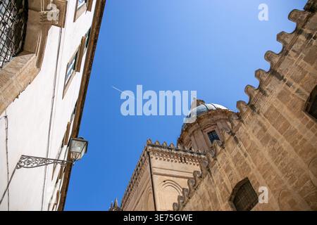 Flacher Blick auf die Kathedrale von Palermo, die ihre historische Architektur gegen den Himmel festnimmt, mit einem Flugzeug, das über dem Himmel vorbeifährt und einen weißen Kondensstreifen hinterlässt Stockfoto