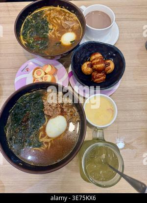 Im Restaurant Miyagi gab es ein japanisches Essen: Zwei Schalen Ramen mit Meeresalgen und Eiern, Takoyaki, Lachs-Sushi und grünem Eistee. Stockfoto