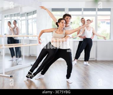 Junge Balletttänzerin, die Partnerin in herausfordernden Bewegungen unterstützt Stockfoto