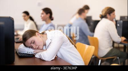 Die junge Frau schlief am Tisch im Büro ein Stockfoto