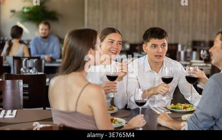 Zwei Paare treffen sich zum Abendessen im Restaurant. Sie unterhalten sich und trinken Wein Stockfoto