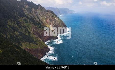 Die Nordküste Madeiras aus der Vogelperspektive zeigt steile vulkanische Klippen, Basaltflächen, Lorbeerwälder, weiße Brandung und weiche, hohe Wolken am milden Tag Stockfoto