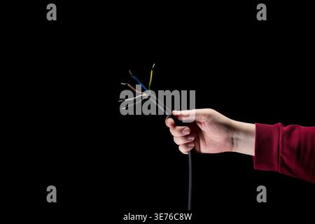 Hand hält freiliegende elektrische Kabel Stockfoto