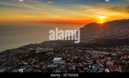 Blick in die Abenddämmerung von Madeira in der Nähe von Camara de Lobos und Funchal. Terrakotta-Dächer, gewundene Küstenstraßen, Terrassen-Hügel und Ackerland führen hinab zum Stockfoto