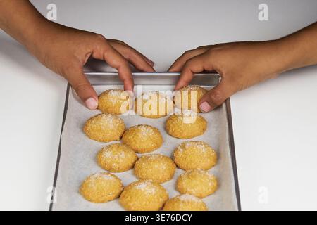 Hände arrangieren runde selbstgemachte Zuckerkekse auf einem mit Backpapier ausgelegten Backpapier Stockfoto