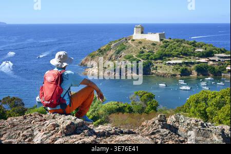 Touristen beobachten die kleine Festung von Girolata vom Fußweg Mare i Monti, Frankreich, Korsika, Girolata Stockfoto
