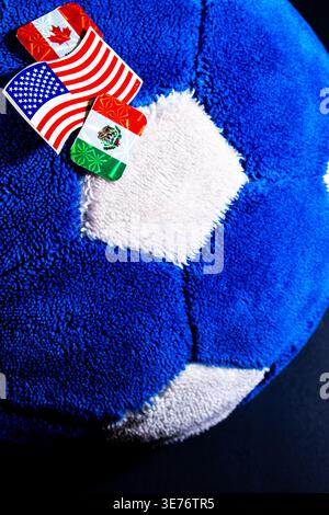Nahaufnahme eines blau-weißen Plüschfußballs mit Aufklebern für die USA, Mexiko und Kanada, die an internationale Sportereignisse erinnern. Stockfoto
