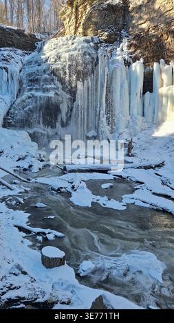 Das Bild zeigt einen wunderschönen Wasserfall, der teilweise im Winter gefroren ist. Die Szene vermittelt Kälte, Natur und Ruhe. Stockfoto