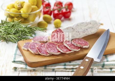 Traditionelle spanische Salami Fuet Wurst mit Rosmarin und Baguet auf einem Schneidebrett aus nächster Nähe Stockfoto