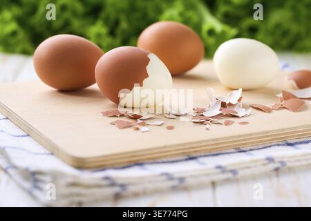 Frische hart gekochte Eier mit Schale neben einem Schneidebrett, selektiver Fokus Stockfoto