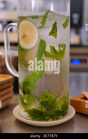 Ein kühles Getränk mit Limette und Pfefferminze steht drinnen auf einem Tisch Stockfoto