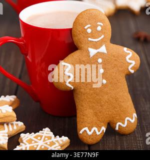 Erstellen Sie eine Weihnachtscollage mit Lebkuchenkeksen und heißer Schokolade auf einem Holztisch Stockfoto