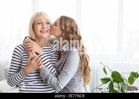 Eine junge Frau, die ihre Mutter auf die Wange küsst Stockfoto