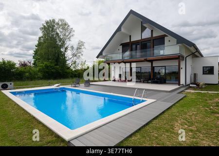Modernes zweistöckiges Haus mit Glasbalkon und Außenpool in einem Vorstadthinterhof Stockfoto