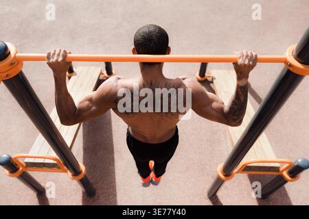 Tätowierter Mann macht Pull-Up-Übung, Draufsicht Stockfoto