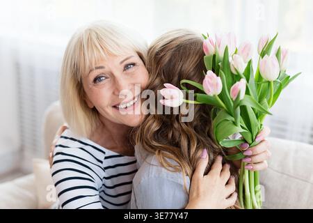 Frau grüßt ihre Mutter mit Geburtstag und umarmt Stockfoto