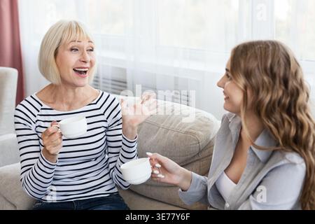 Glückliche, reife Mutter und Tochter trinken Kaffee und reden Stockfoto