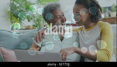 Afroamerikaner Senior Mutter und Tochter sitzen zu Hause auf der Couch mit Laptop-Luftpolsterüberzug Stockfoto