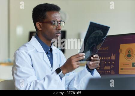 Afroamerikanischer Arzt untersucht Gehirnscan in der Klinik, überprüft diagnostische Bildgebung für neurologische Beurteilung. Ideal für Gesundheitstechnologie, Diagnose, telemedizinisches Marketing Stockfoto