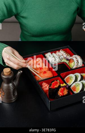 Mädchen isst asiatisches Essen aus der bento-Box mit Essstäbchen Stockfoto