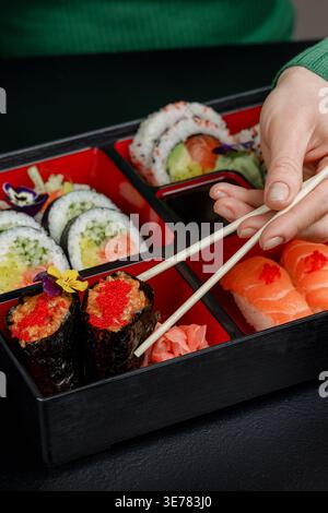 Mädchen isst asiatisches Essen aus der bento-Box mit Essstäbchen Stockfoto