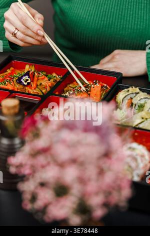 Mädchen isst asiatisches Essen aus der bento-Box mit Essstäbchen Stockfoto