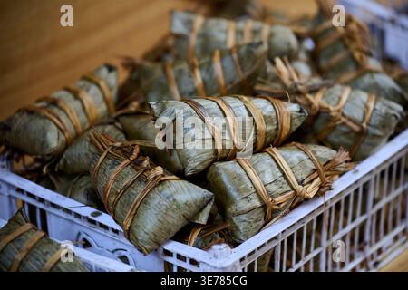 Traditionelle chinesische Zongzi-Klebereisknödel in Blätter gewickelt und mit Schnur in einer Plastikkiste gebunden, Shanghai, China, Asien. Stockfoto