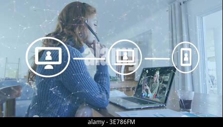 Arbeitende Frau mit blauem Headset Beratung auf Laptop zu Hause mit Diagrammen, Netzwerksymbolen Stockfoto