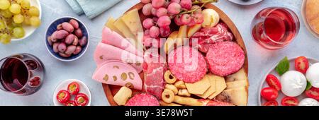 Italienisches Antipasti-Panorama. Wurstplatte mit Käse und anderen Snacks, mit Wein, Oliven, Obst usw. Panoramaaufnahme über Kopf mit Flachlage Stockfoto