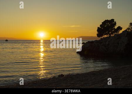 Goldener Sonnenuntergang über der Adria mit Sonnenspiegelung auf ruhigem Wasser. Friedliche Küstenlandschaft in Kroatien. Stockfoto