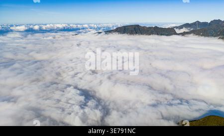 Bei Tageslicht aus der Vogelperspektive werden Madeiras Hochland als Wolken bedeckt, wobei Pico do Arieiro und Pico Ruivo über der Wolkenumkehr unter dem Klon aufsteigen Stockfoto